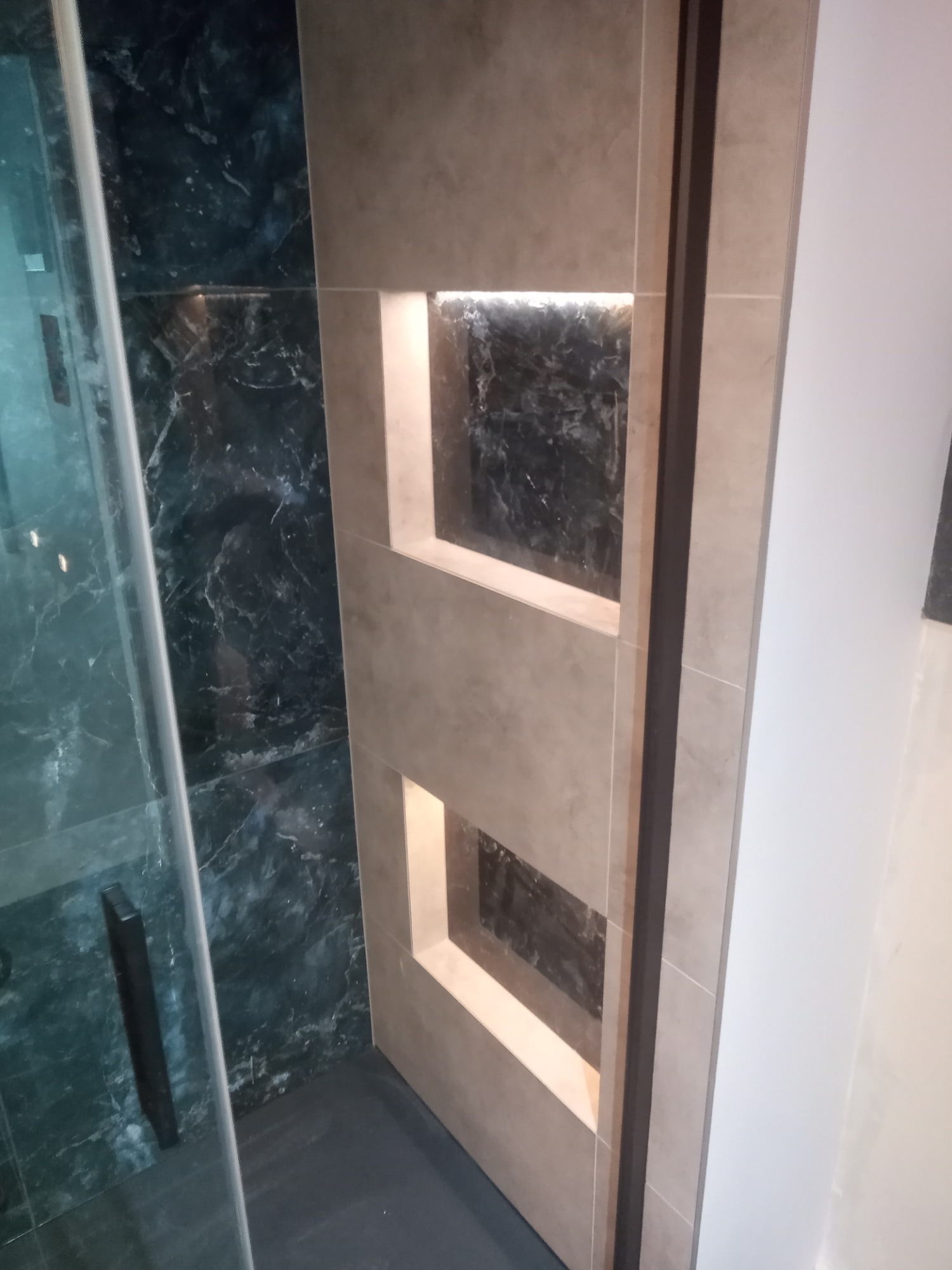 Wykończona łazienka w Gdańsku z kabiną prysznicową i ścianą z szarych płytek z wnękami podświetlonymi od wewnątrz.