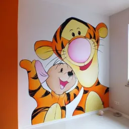 Ręcznie malowana ściana w pokoju dziecięcym z postaciami z bajki Kubuś Puchatek: Tygrysek i Prosiaczek, widoczne z bliska, z jasną podłogą i pomarańczową ścianą boczną.