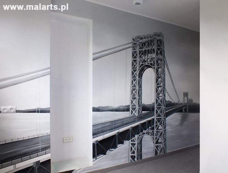 Czarno-biała iluzja optyczna na ścianie przedstawiająca most wiszący, z widocznymi gniazdkami elektrycznymi, sugerująca realizm malunku.
