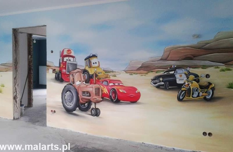 Ilustracja na ścianie przedstawiająca postacie z filmu Auta na tle pustynnego krajobrazu, wykonana w pomieszczeniu w trakcie remontu.