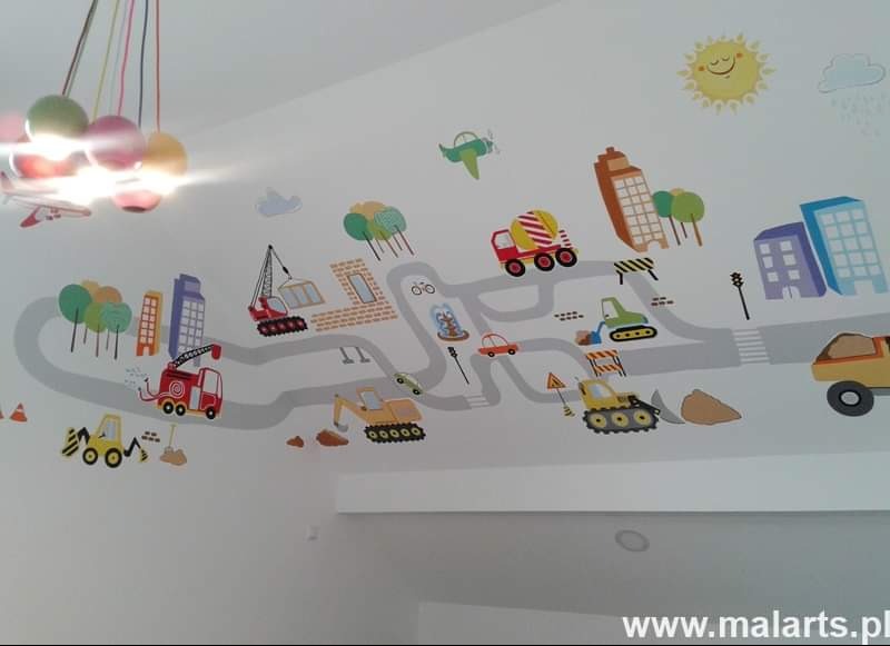 Dziecięcy pokój z dekoracyjną, ręcznie malowaną ścianą przedstawiającą krajobraz miejski z budynkami, drogami i pojazdami budowlanymi, stylizowany na rysunek dla dzieci.