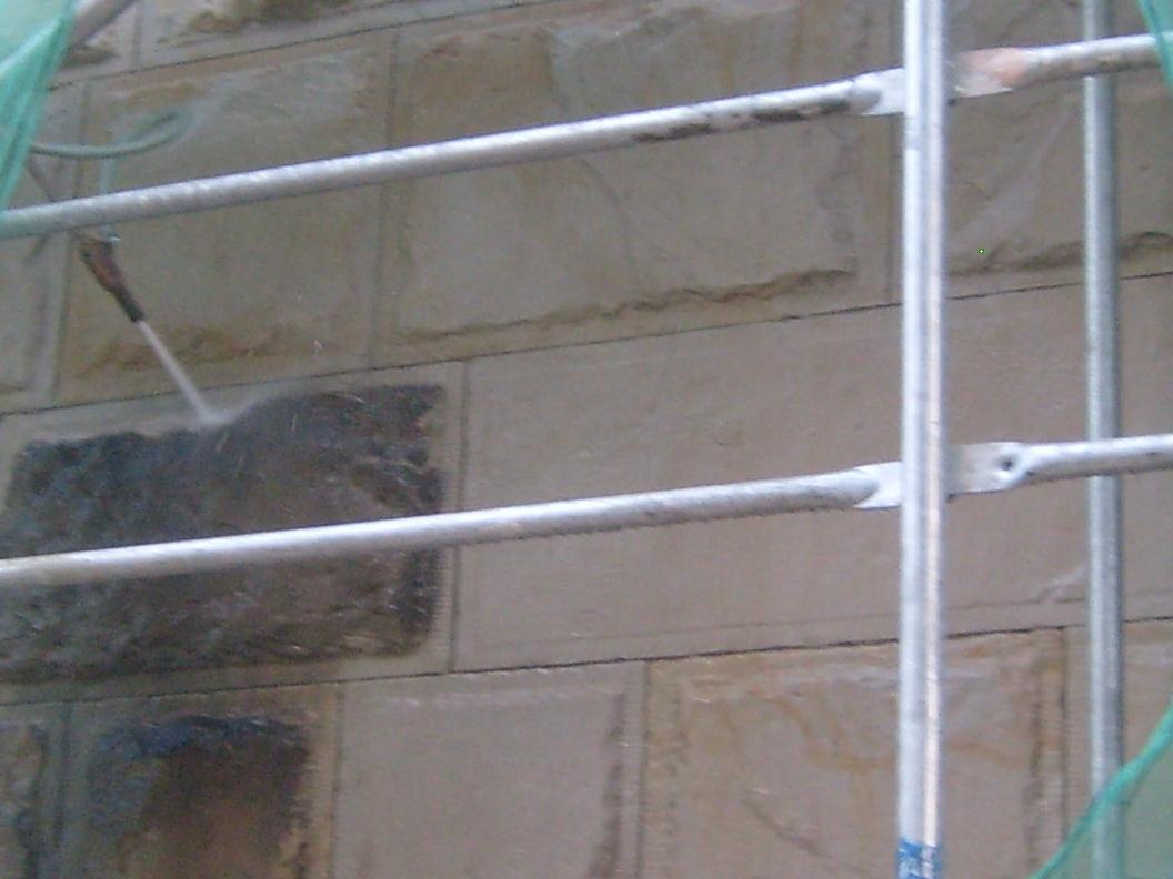 Czyszczenie ciśnieniowe fragmentu kamiennej elewacji z rusztowania, widoczna różnica w kolorze między czyszczonym a nieczyszczonym obszarem.