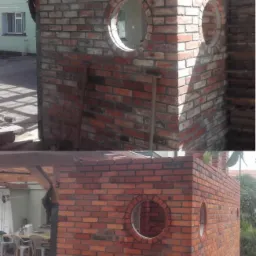 Konstrukcja z czerwonej cegły z okrągłymi otworami okiennymi, w trakcie budowy, widoczne niedociągnięcia w spoinowaniu.