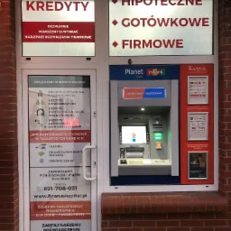 Fasada placówki finansowej z reklamami kredytów hipotecznych, gotówkowych i firmowych oraz bankomatem Planet Cash i Mbank. Na drzwiach informacje o kredytach konsolidacyjnych, samochodowych...