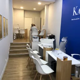 Wnętrze biura doradcy finansowego z białymi krzesłami, biurkami z komputerami i plakatem firmy Kapitał na niebieskiej ścianie.