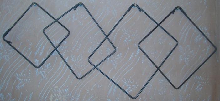 Połączone strzemiona zbrojeniowe w kształcie rombów, zawieszone na ścianie z delikatnym wzorem.