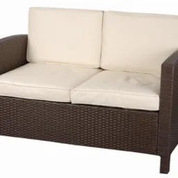 Dwuosobowa sofa ogrodowa z brązowego rattanu syntetycznego z kremowymi poduszkami siedziskowymi i oparciowymi, prezentowana na białym tle.