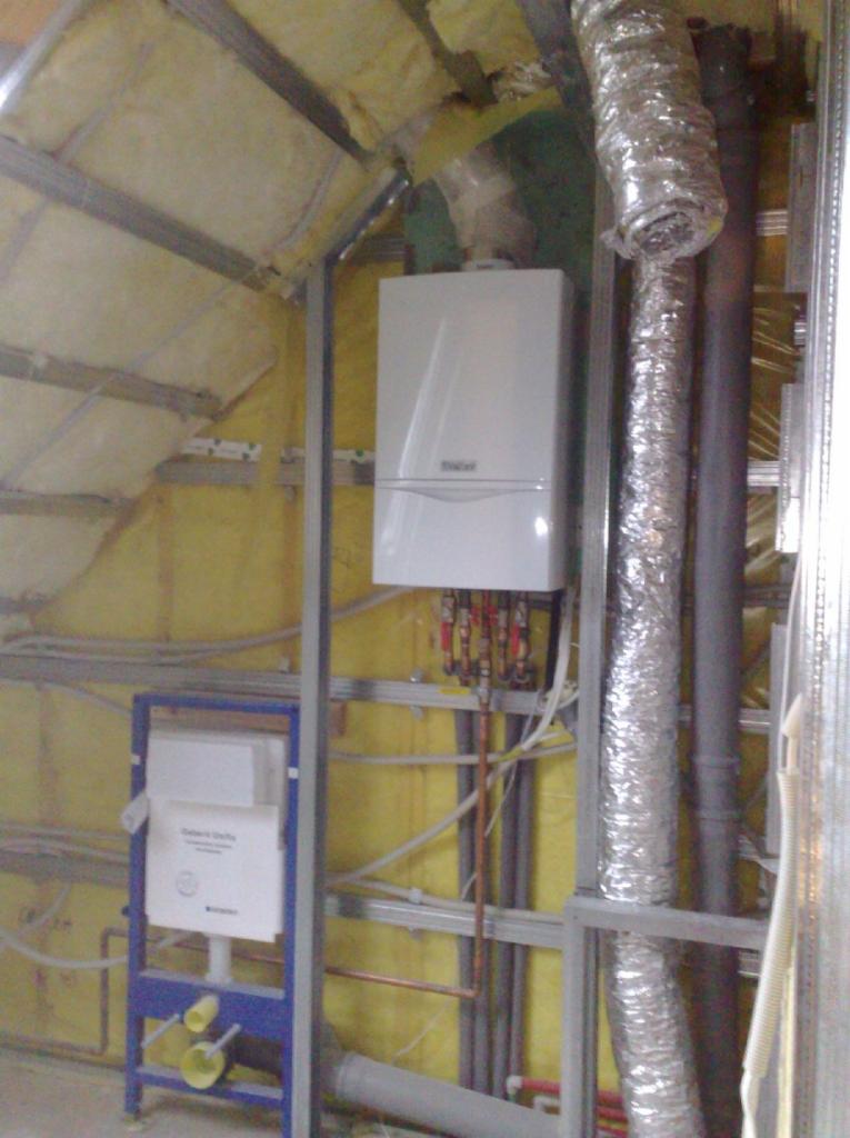 Montaż instalacji grzewczej i sanitarnej w nowo budowanym domu: biały piec gazowy Vaillant, rury miedziane, izolowana rura wentylacyjna, stelaż podtynkowy WC Geberit, ściany z płyt g-k i wełny...