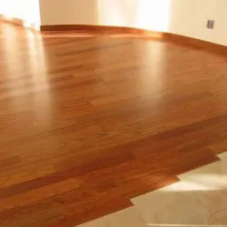 Świeżo położony parkiet z egzotycznego drewna, widoczny fragment łączenia z płytkami ceramicznymi przy ścianie.