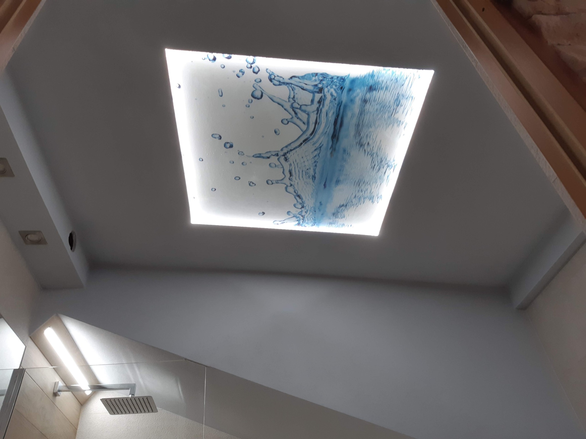 Nowoczesna łazienka z kabiną prysznicową i podświetlanym sufitem z motywem wodospadu, widok z dołu.