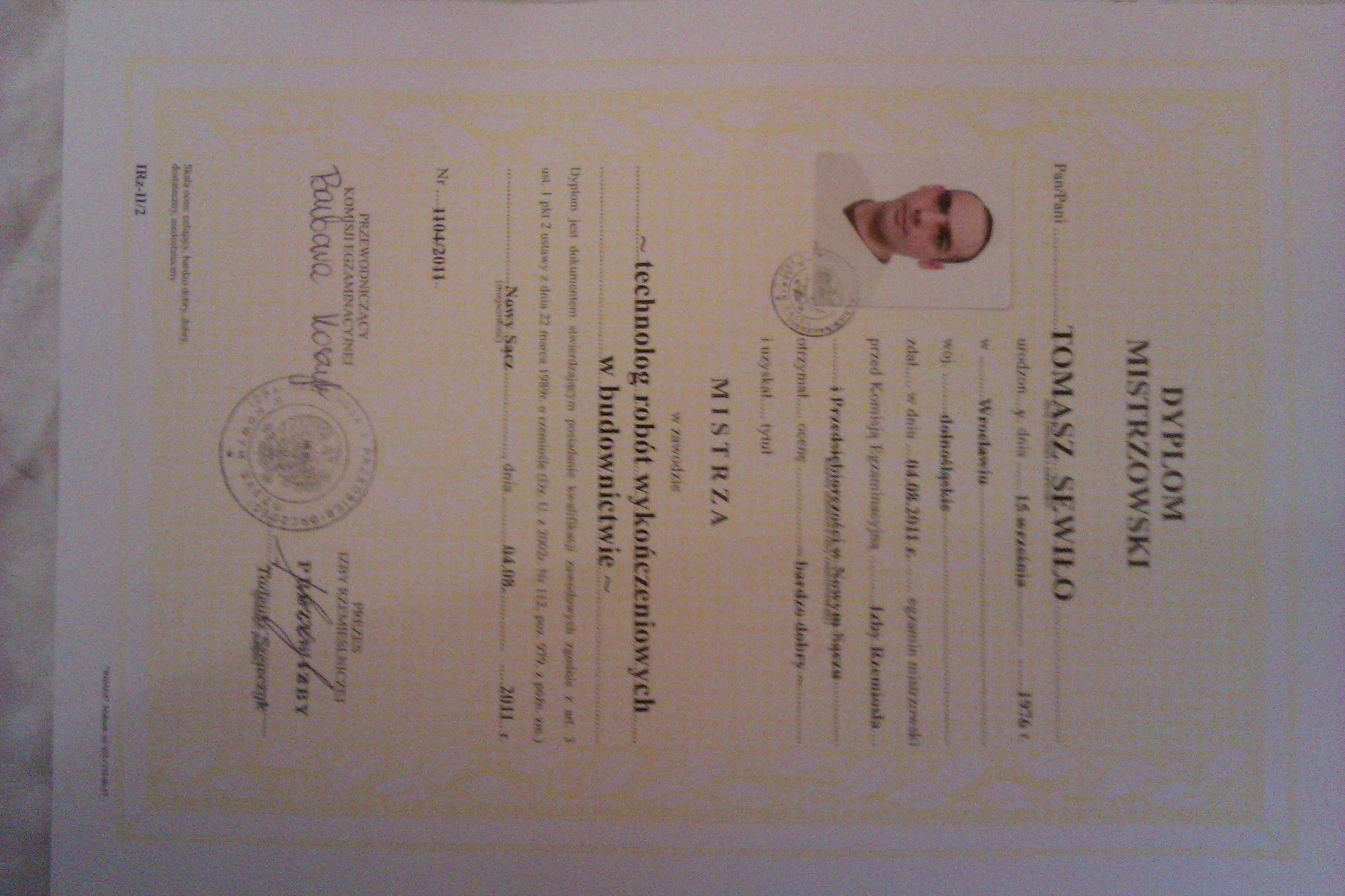 Skan dyplomu mistrzowskiego technologa robót wykończeniowych w budownictwie, wydany w 2011 roku, z pieczęciami i podpisami, z widocznym zdjęciem właściciela.