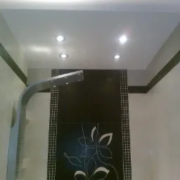 Wykończona łazienka z czarną ścianą z motywem kwiatowym, szarym panelem prysznicowym i oświetleniem punktowym w suficie.