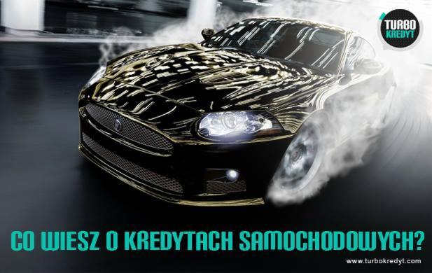 Czarny samochód sportowy w dynamicznym ujęciu z efektem dymu wokół kół, na tle rozmytej przestrzeni miejskiej, z logo 'TURBO KREDYT' w prawym górnym rogu i pytaniem 'Co wiesz o kredytach...