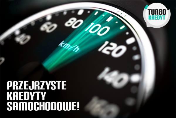 Licznik samochodu wskazujący 100 km/h z zielonym podświetleniem, logo 'TURBO Kredyt' w prawym górnym rogu, napis 'PRZEJRZYSTE KREDYTY SAMOCHODOWE!' na dole.