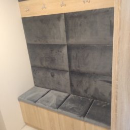 FHU Art-primus - Szafa wnękowa z siedziskiem wykończonym szarymi panelami tapicerowanymi, drewniany panel z wieszakami na ubrania.