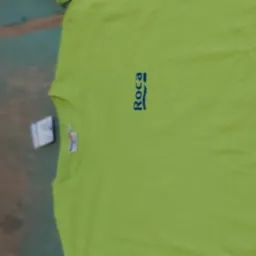 Jasnozielona koszulka z krótkim rękawem i niebieskim logo Roca, leżąca na nierównym tle z etykietą