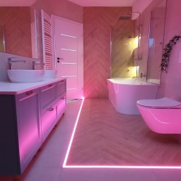 KABUD Kamil Karkowski - Nowoczesna łazienka z podświetleniem LED w kolorze różowym, umywalki nablatowe, biała wanna i toaleta, drewnopodobna podłoga ułożona w jodełkę.