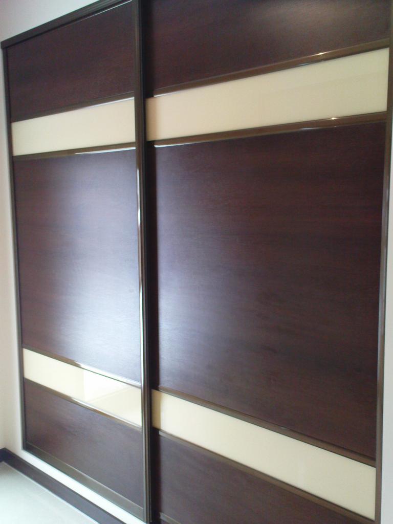 Dwudrzwiowa szafa przesuwna z ciemnego drewna z poziomymi wstawkami z mlecznego szkła, widok z bliska.