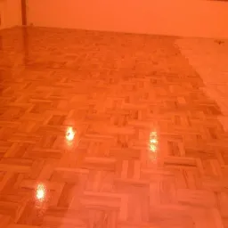 Parkiet po cyklinowaniu w Siedliskach, z widocznym fragmentem powierzchni przed i po zabiegu, ukazując różnicę w wyglądzie.