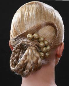 Upięcie blond włosów z warkoczem i ozdobnymi, złotymi kulkami, widok z tyłu na czarnym tle.