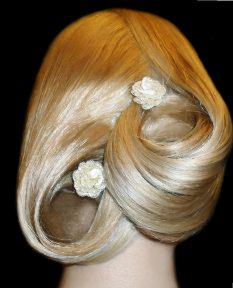 Upięcie blond włosów z dwoma dekoracyjnymi kwiatami, widok z tyłu, stylizacja ślubna.