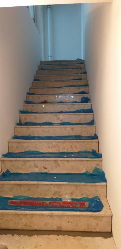 Marmurowe schody zabezpieczone folią ochronną podczas remontu w Lubiczynie, na jednym ze stopni poziomica w czerwonej obudowie.