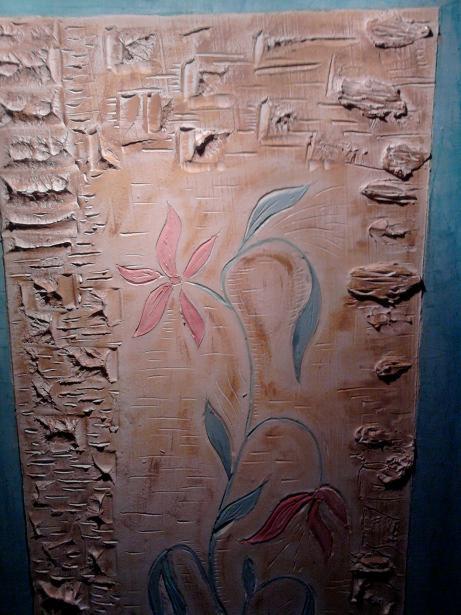 Dekoracyjna ściana z fakturą imitującą kamień i motywem kwiatowym w odcieniach różu i zieleni, z wyraźną strukturą i oświetleniem podkreślającym detale.