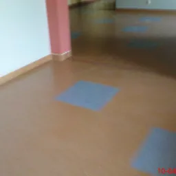 Brązowa podłoga z kwadratowymi, szarymi wstawkami, widok z góry, ściany białe i różowe.