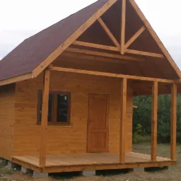 Drewniany domek letniskowy z brązowym dachem i otwartą werandą, widok z przodu na tle zieleni. Konstrukcja z jasnego drewna, okno i drzwi w ciemniejszym odcieniu brązu.