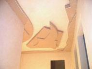 Niedokończony sufit z płyt kartonowo-gipsowych z widocznymi elementami konstrukcyjnymi i szpachlowaniem na ścianach, w trakcie remontu.