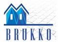 Logo firmy brukarskiej BRUKKO na tle planu kostki brukowej. Logo przedstawia dwa stylizowane domki z niebieskimi dachami.
