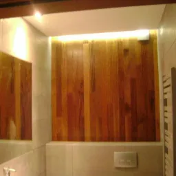 Nowoczesna łazienka z drewnianą okładziną ściany, ukryte oświetlenie LED nad okładziną, widok z lustra.