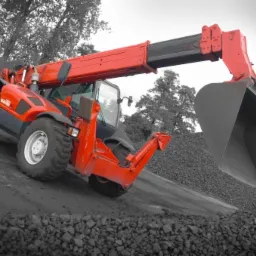 Czerwona ładowarka teleskopowa nabiera węgiel na tle czarno-białego krajobrazu. Widoczne opony i ramię z łyżką. Praca na składzie opału.