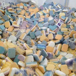 Worek wypełniony mieszanką kolorowych tabletek do zmywarek (pomarańczowe, niebieskie, fioletowe) oraz granulowanego proszku, niektóre tabletki w przezroczystych foliowych opakowaniach z logo 'W5'.