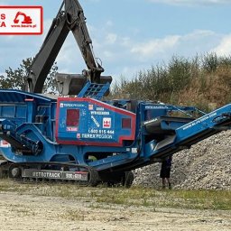 BAURS POLSKA - SPÓŁKA CYWILNA: SIDOROWICZ INGA, SIDOROWICZ ROBERT - Mobilny kruszacz szczękowy Terex Pegson Metrotrak 900x600 w kolorze niebieskim z logo firmy Baur's Polska, na tle zieleni i gruzu.