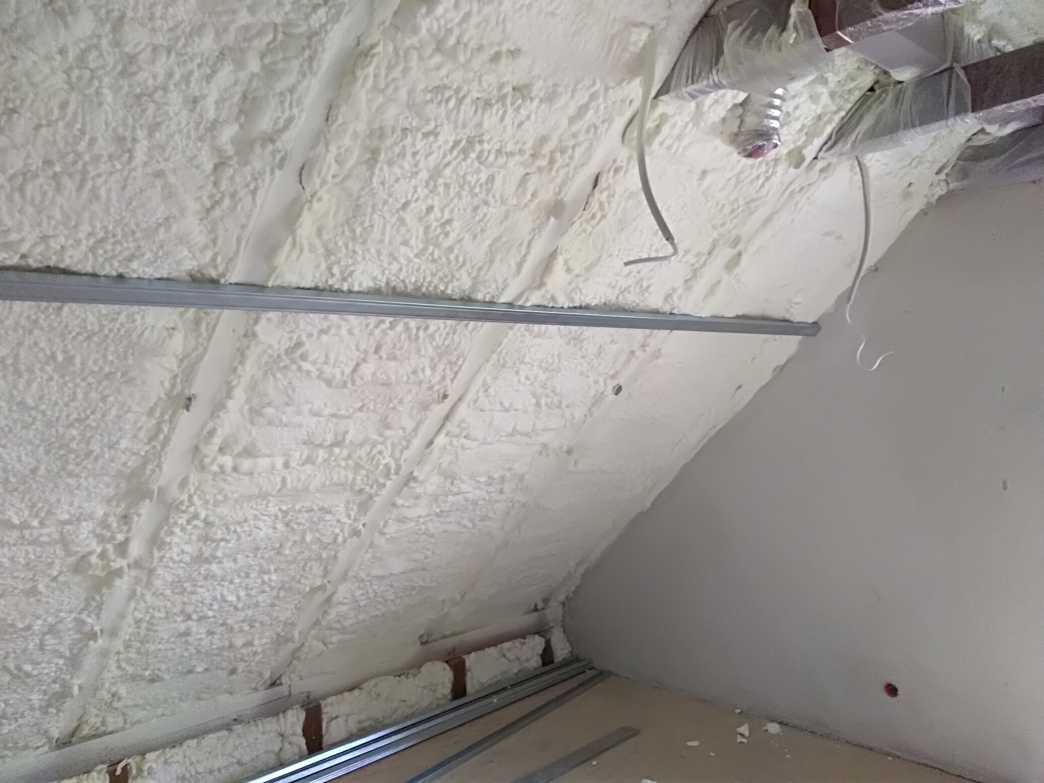 Poddasze po ociepleniu pianką PUR, widoczne metalowe profile konstrukcyjne i fragment instalacji wentylacyjnej pod sufitem.