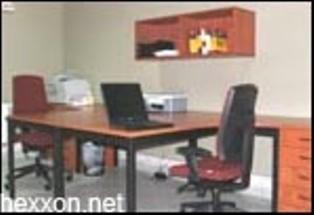 Biuro z biurkiem, krzesłami, laptopem i drukarką, sugerujące pracę biurową związaną z finansami i rachunkowością.