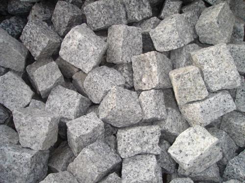 Góra szarych, surowych, granitowych sześcianów o nieregularnej fakturze, przeznaczonych do budowy nawierzchni.