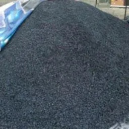 Góra czarnego ekogroszku Pieklorz z kopalni Bobrek, częściowo przykryta szarą plandeką, widoczna w tle konstrukcja ogrodzenia.