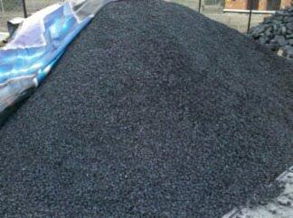 Góra czarnego ekogroszku Pieklorz z kopalni Bobrek, częściowo przykryta szarą plandeką, widoczna w tle konstrukcja ogrodzenia.