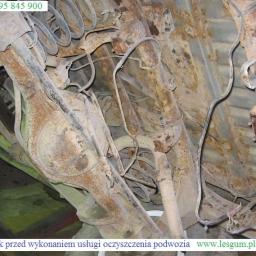 Kooperacja Polsko-Niemiecka LES-GUM Export-Import Leszek Wydrzyński - Zardzewiałe podwozie Jeepa przed czyszczeniem w Dębicy. Widoczne elementy zawieszenia i liczne ogniska korozji. Ujęcie od dołu.