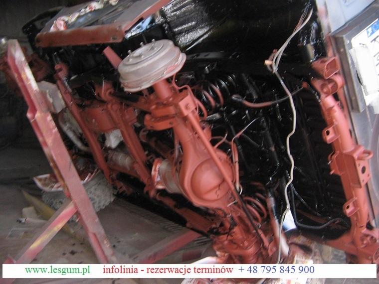 Podwozie auta po renowacji: czerwone elementy zawieszenia i czarna rama, widoczne sprężyny i elementy układu hamulcowego. Ujęcie z dołu, obrócone.