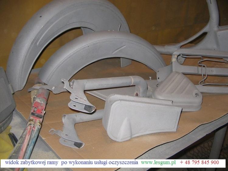 Elementy zabytkowej ramy motocykla po oczyszczeniu, przygotowane do dalszej obróbki. Widoczne błotniki, rama i inne części w szarym, matowym wykończeniu.