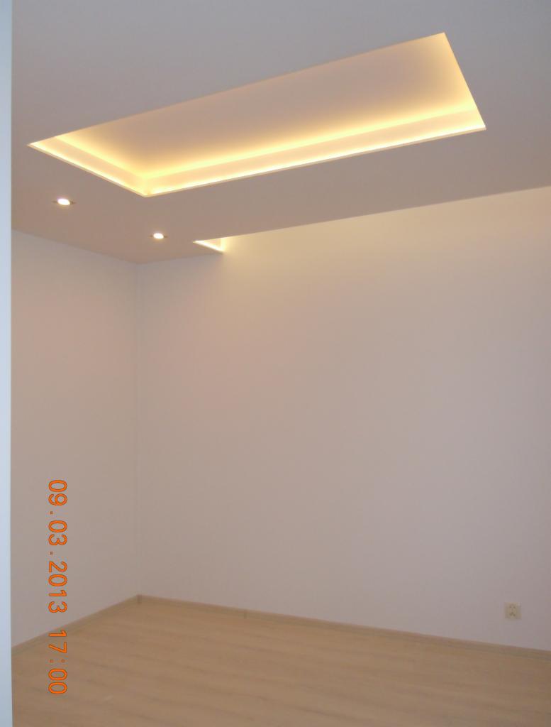 Pusty, jasny pokój z podwieszanym sufitem z oświetleniem LED, widok na sufit i część ścian, parkiet na podłodze.