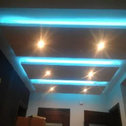 Kaskadowy sufit podwieszany z podświetleniem LED w kolorze turkusowym, tworzący efektowną grę świateł i cieni w nowoczesnym wnętrzu.