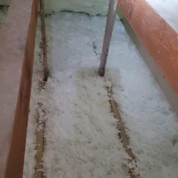 Poddasze ocieplone białą pianką PUR, widoczne drewniane elementy konstrukcji dachu.