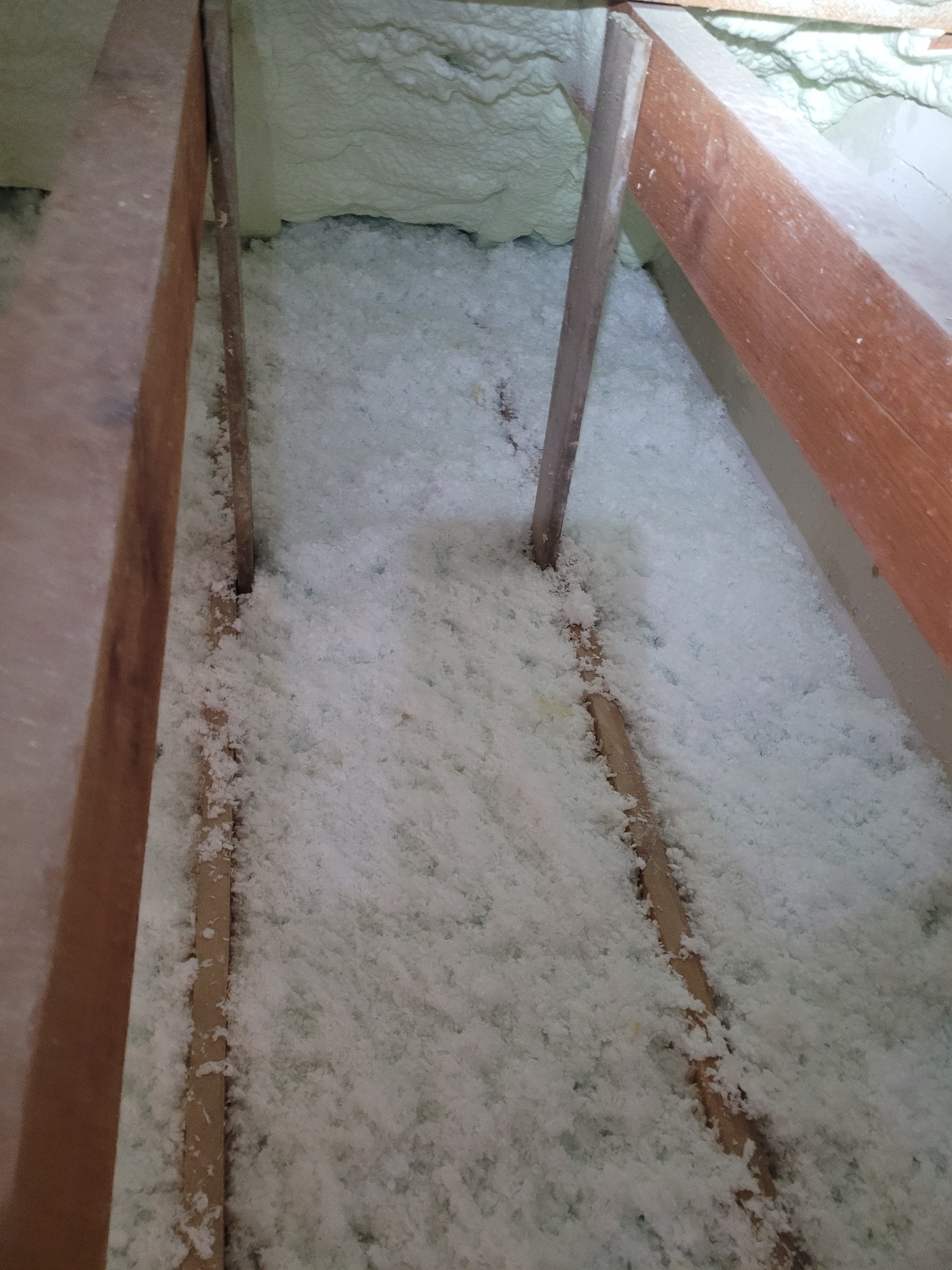 Poddasze ocieplone białą pianką PUR, widoczne drewniane elementy konstrukcji dachu.