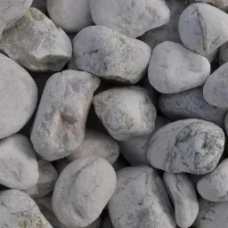 Stos białych, otoczaków rzecznych o zróżnicowanej fakturze i odcieniach szarości, przeznaczonych do dekoracji ogrodów lub jako element wykończeniowy.