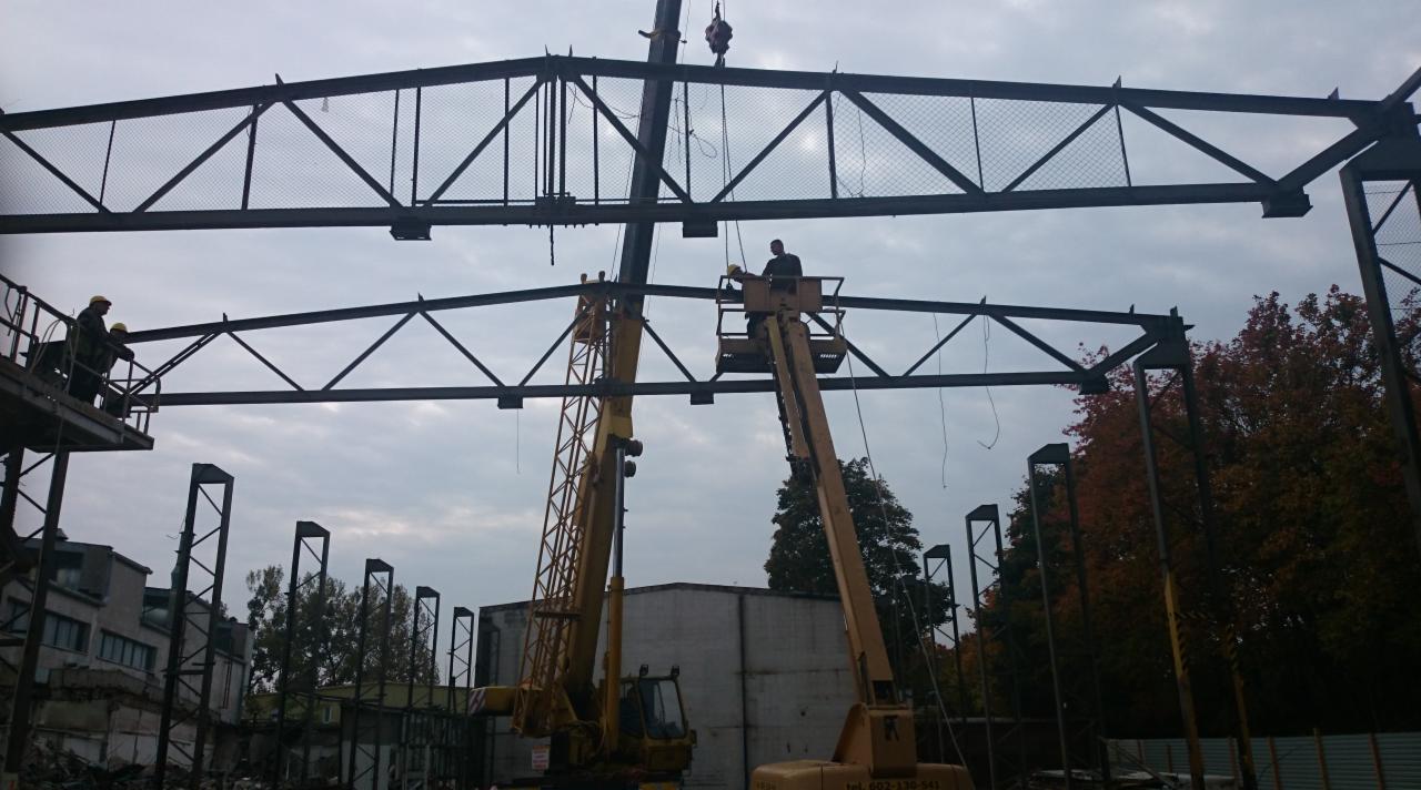 Montaż konstrukcji stalowej z użyciem dźwigu i podnośnika koszowego w Gdańsku. Widoczni pracownicy w trakcie pracy na wysokości.