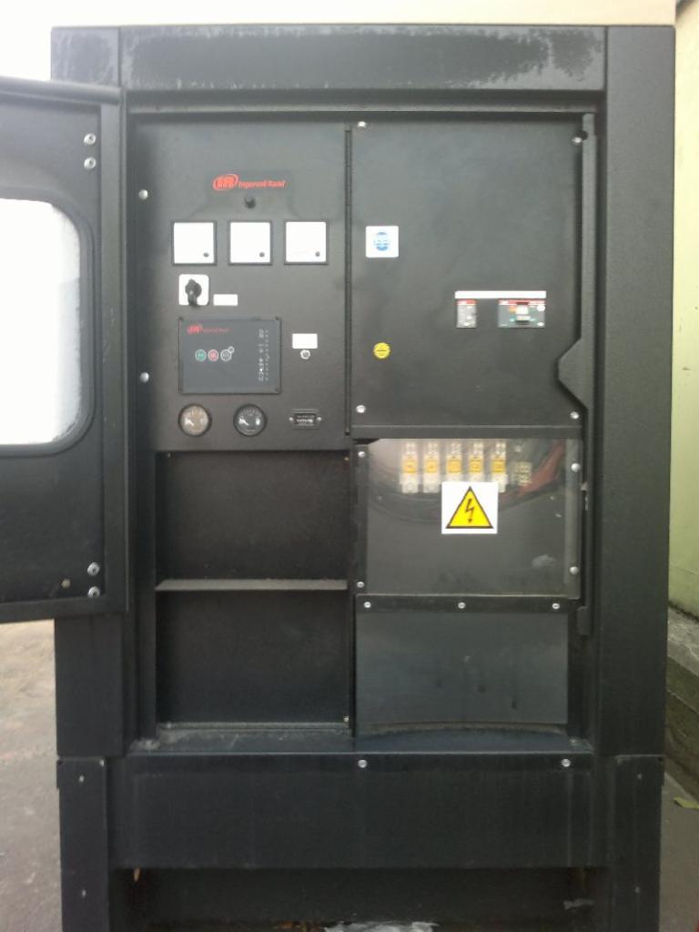 Czarny generator prądu Ingersoll Rand G60 z otwartymi drzwiczkami, widoczne wskaźniki, przełączniki i ostrzeżenie o wysokim napięciu.